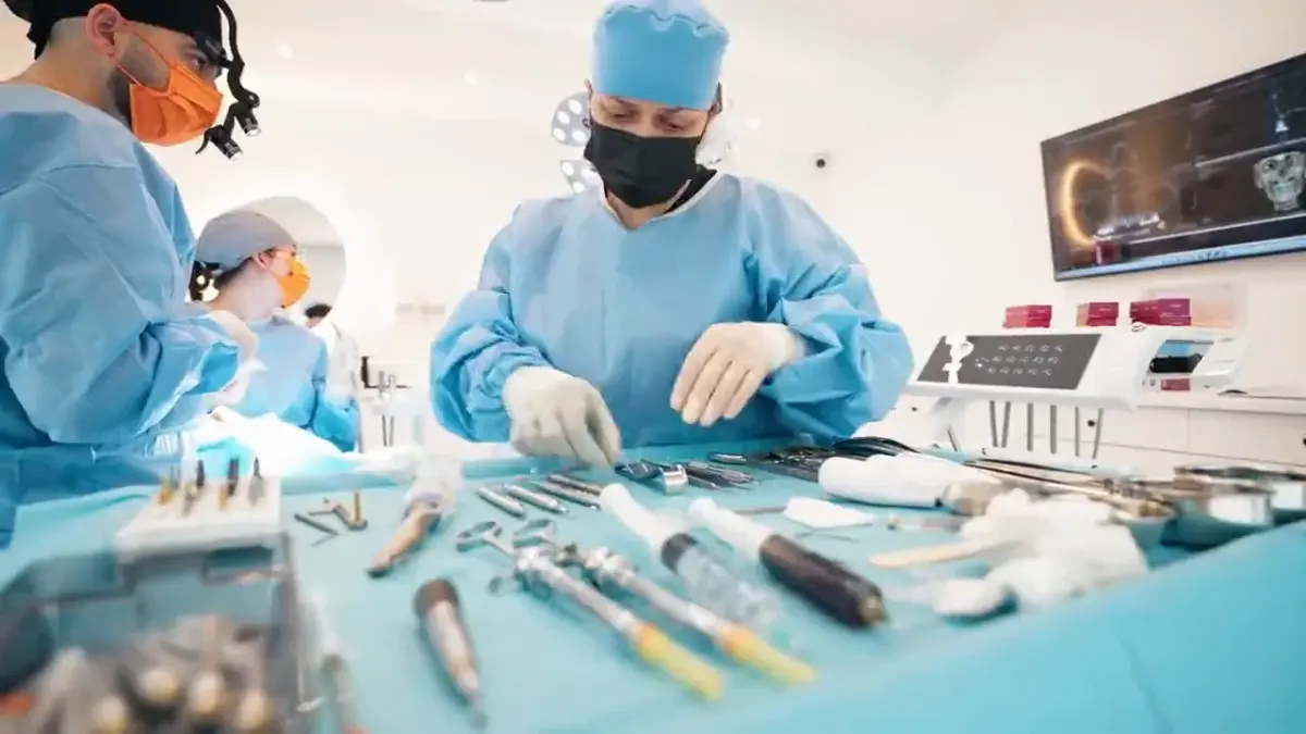Asistenta îi dă medicului un instrument, în timpul unei intervenții de implantologie